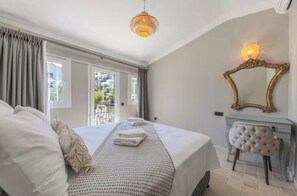 Un dormitorio con una cama grande, un tocador con espejo y vistas a través de una ventana.