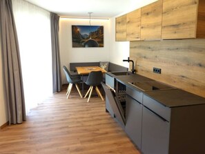 Eine moderne Küche mit Holzausstattung, ein Essbereich mit Tisch und Stühlen sowie ein Gemälde an der Wand.