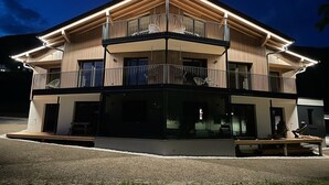 A two-story building with a balcony on the upper level, a covered entrance, and a visible outdoor seating area. - Apartment  by Interhome (Saalbach-Hinterglemm)