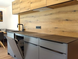 Eine moderne Küche mit Holzschränken, einem eingebauten Geschirrspüler und einer Arbeitsplatte.