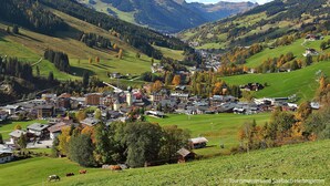 A mountainous town with a central building surrounded by houses, a ski lift, and a green valley. - Apartment  by Interhome (Saalbach-Hinterglemm)