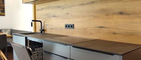 A modern kitchen with wooden cabinetry, a stainless steel sink, and a dishwasher.