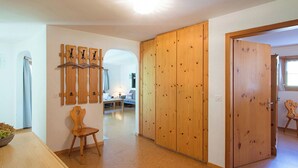 A room with a wooden wardrobe, a chair, a table, and a wall-mounted wooden art piece. - Ferienhaus Muntschi, (Andeer), by Interhome (Andeer)