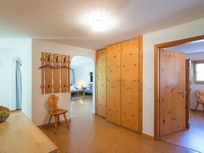 A room with a wooden wardrobe, a chair, a table, and a wall-mounted wooden art piece. - Ferienhaus Muntschi, (Andeer), by Interhome (Andeer)
