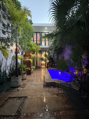 Ein Innenhof mit Swimmingpool, Topfpflanzen und einem Gebäude im modernen Stil.