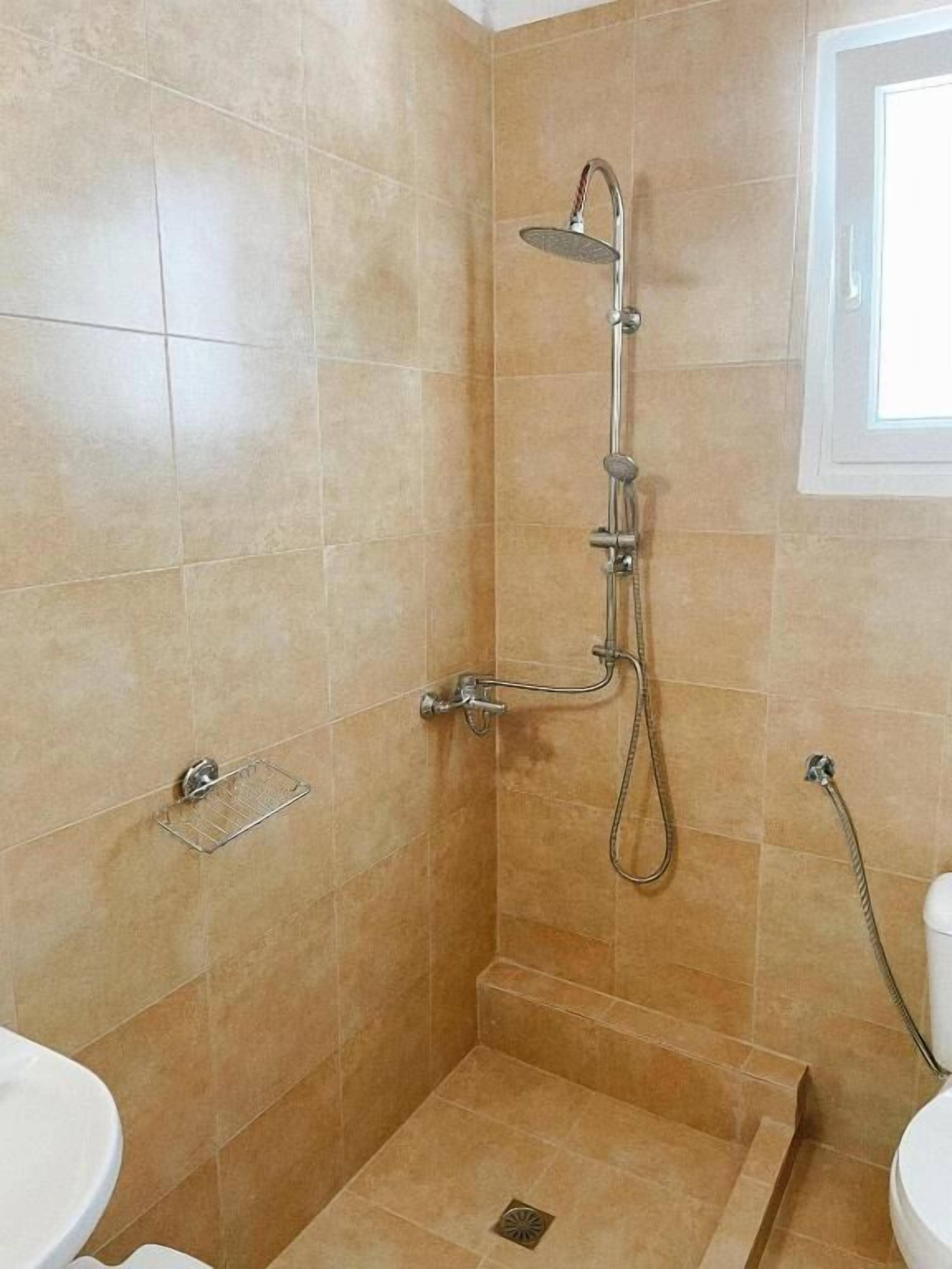 A small, tiled bathroom with a shower, a toilet, and a sink.
