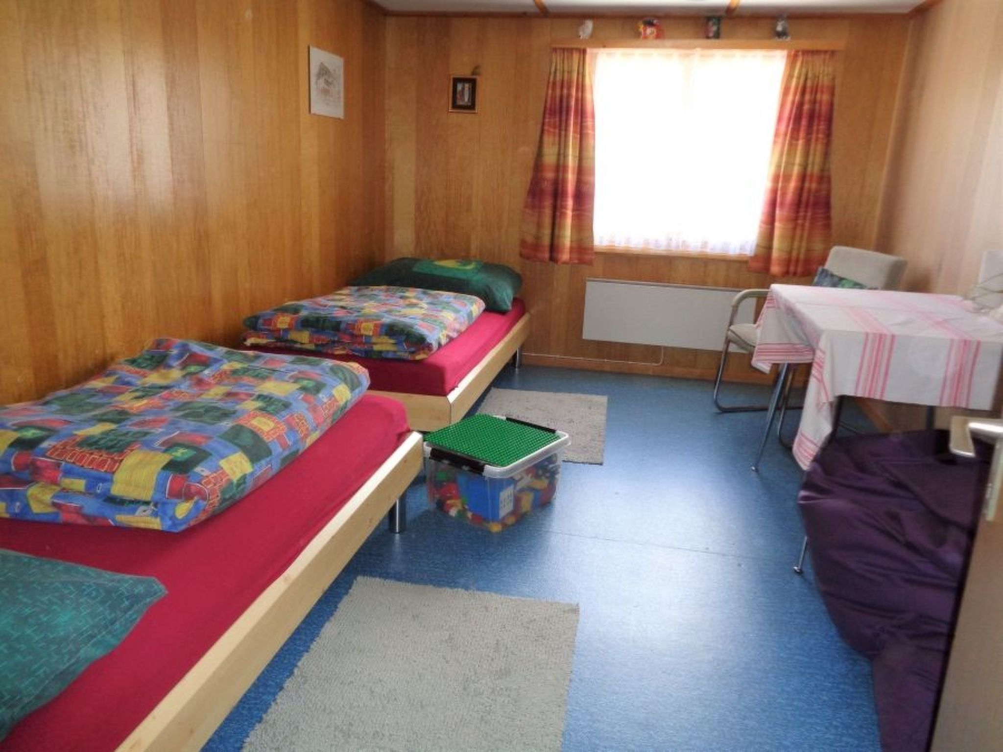 Ein Zimmer mit zwei Betten, einem kleinen Tisch und einem Stuhl.