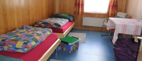 A room with two beds, a small table, and a chair.