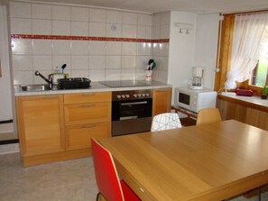 A compact kitchen with a stove, oven, microwave, and sink. There is a dining table with chairs. - Tulipana Berther, (Sedrun), 103.05 by Interhome (Sedrun)