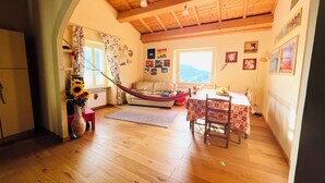 Una habitación acogedora con techo de madera, una hamaca, un sofá, una mesa de comedor con sillas y vistas al exterior.