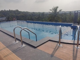 A swimming pool with metal railings, surrounded by a wooden deck.