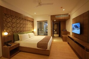 Habitación de hotel con cama, mesita de noche, televisor y vistas al exterior.