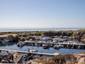En lysthavn med fortøjede både, en klippefyldt kystlinje og frit udsyn til havet.