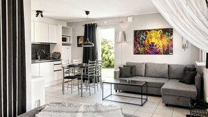 Um apartamento moderno com cozinha compacta, área de refeições, sofá e uma pintura grande.