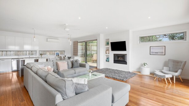 A modern living room with a grey sectional sofa, a flat-screen TV mounted on the wall, and a fireplace. - Premium Location Family and Pet Friendly Property (Torquay)