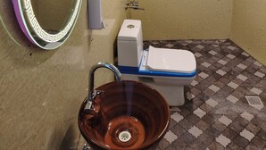 A bathroom with a toilet, sink, mirror, and a water heater. - North Cliff by Stay Pattern (Gund)