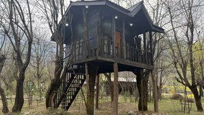 A treehouse with a wooden exterior, a staircase, and a balcony. - North Cliff by Stay Pattern (Gund)