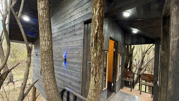 A wooden cabin with a covered porch, a bench, and a door leading inside. - North Cliff by Stay Pattern (Gund)