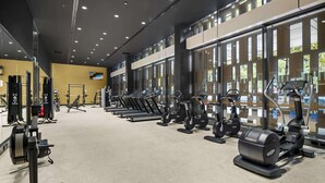 Uma academia com esteiras, elípticos e equipamentos de musculação.