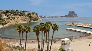 A coastal town with a beach, palm trees, and a rocky outcrop in the distance. - Casa Timeris 8 pax - Calpe, Costa Blanca (Calpe)