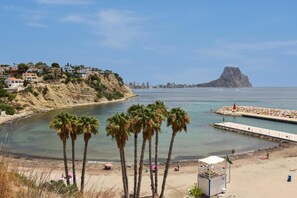 A coastal view with palm trees, a beach, and a rocky outcrop in the distance. - Casa Timeris 8 pax - Calpe, Costa Blanca (Calpe)