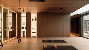 A spacious room with wooden flooring, a yoga mat area, and a wall-mounted rack with various items. - Modern Studio in the City Center Gym and Game Room (Katowice)