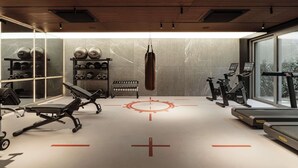A modern gym with exercise equipment, a punching bag, and a large window. - Modern Studio in the City Center Gym and Game Room (Katowice)