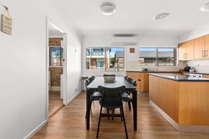 A modern kitchen with a dining area, wooden cabinets, and a large window providing a view of the outside.