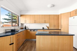 A modern kitchen with wooden cabinets, a black countertop, and a built-in dishwasher.