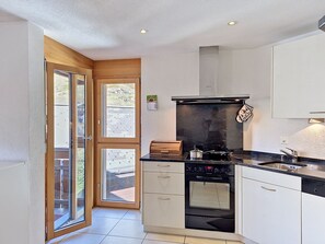 A modern kitchen with a built-in oven, a black countertop, and a window with a view of the outdoors. - Apartment Carlos by Interhome (Zermatt)