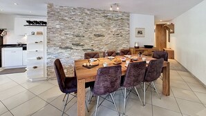 Un espace de salle à manger moderne avec un mur en pierre, une table en bois et des chaises foncées.