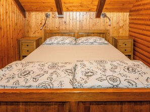 Ein Zimmer mit Holzwänden, einem Bett, zwei Nachttischen und einer Deckenleuchte.