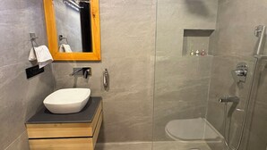 Ett modernt badrum med en duschavdelning med glasväggar, ett badrumsskåp i trä med en tvättställ och en spegel ovanför skåpet.