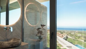 A modern bathroom with a large mirror, a bowl sink, and a view of the ocean. - Esse Villa, a Linear Sea-View Wellness Retreat (Maroulas)