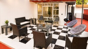 An outdoor patio with a checkered floor, wicker furniture, a glass table, and string lights. - Full house in Condesa, 4 bedrooms, terrace and 3 levels (Ciudad de México)