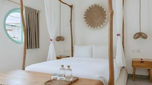 Een hemelbed met een baldakijn, een ronde spiegel, een houten nachtkastje en een dienblad met flessen op het nachttafeltje.