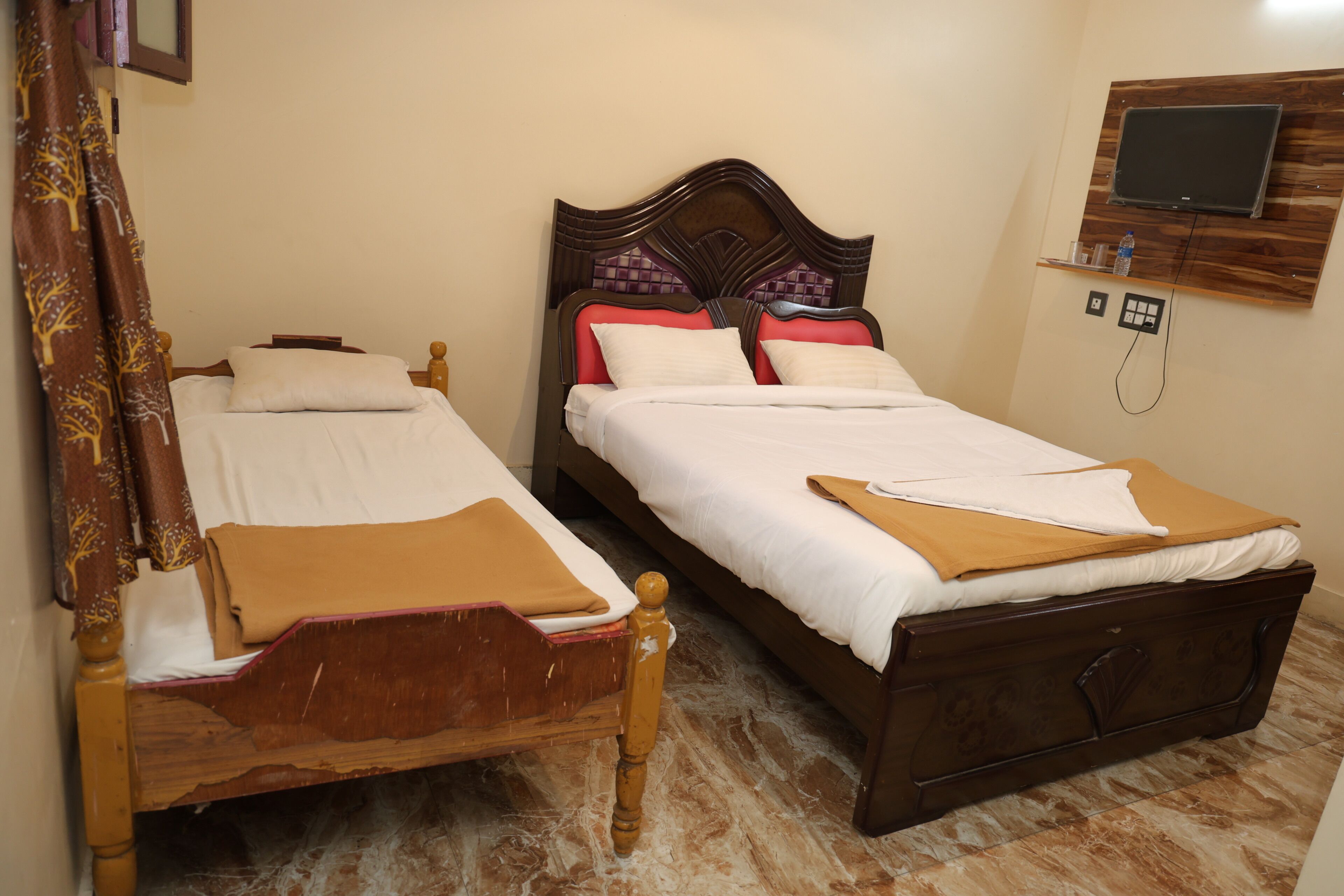 A double bed with a wooden headboard and footboard, a bedside table, and a wall-mounted TV.