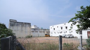 Un recinto vallado con edificios, un camino de tierra y vehículos.