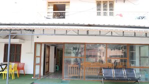 Un edificio con una entrada cubierta, un área de descanso con sillas y un banco en el exterior.