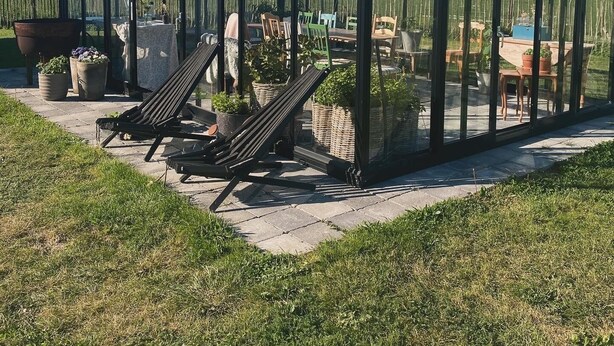 A greenhouse with a glass roof, a patio area with chairs and tables, and potted plants. - Rural house in a peaceful location with wonderful views of the Scanian plains. (Svedala)