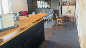 A modern interior with a wooden reception desk, a stone wall, a seating area with a sofa and chairs, and a dining table with chairs. - Rural house in a peaceful location with wonderful views of the Scanian plains. (Svedala)