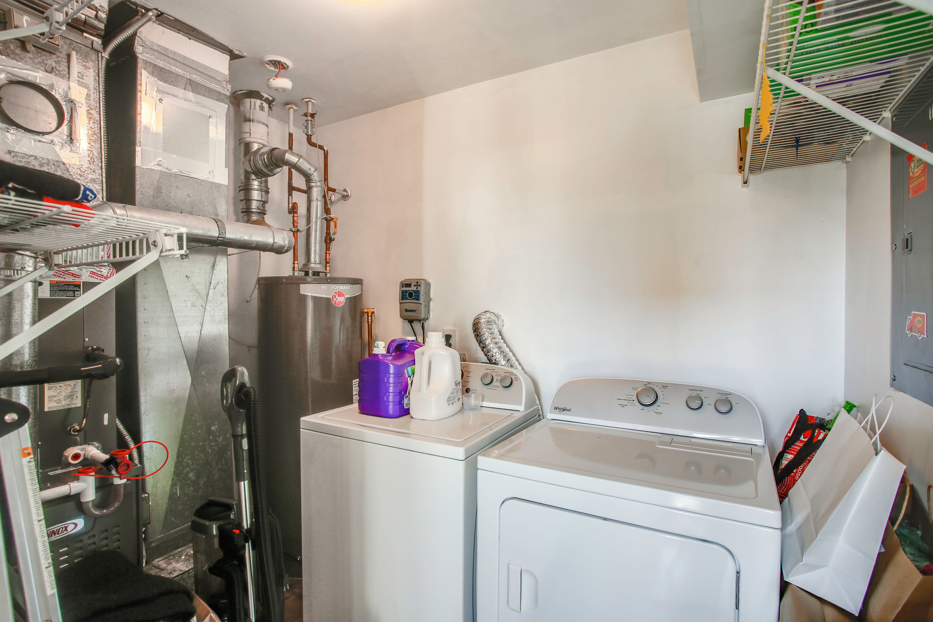 A laundry area with a washing machine, dryer, and various cleaning supplies.