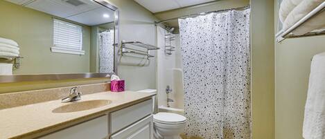 Baño con lavamanos, inodoro, ducha y espejo con luces.