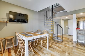 A dining area with a table, chairs, and a TV mounted on the wall.