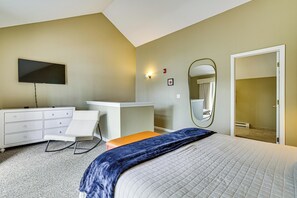 A bedroom with a bed, a dresser, a TV, a mirror, and a door.