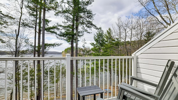 Une terrasse avec vue sur un lac, entourée d’arbres, et comprenant une table et des chaises.