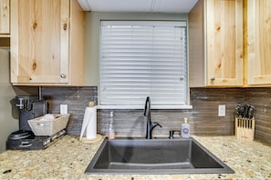 A kitchen with a built-in sink, a coffee maker, a bottle of hand soap, and a knife block.
