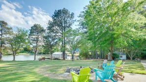 A grassy outdoor area with Adirondack chairs, a small fire pit, and a lake in the background. - Dock Access! Family Retreat on the Little Wicomico (Heathsville)