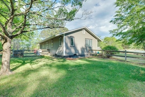 A single-story house with a sloped roof, a fenced yard, and a large tree in the foreground. - Dock Access! Family Retreat on the Little Wicomico (Heathsville)