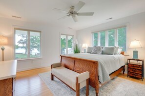 Ein Schlafzimmer mit Bett, einer Bank, einem Nachttisch und einem Deckenventilator.